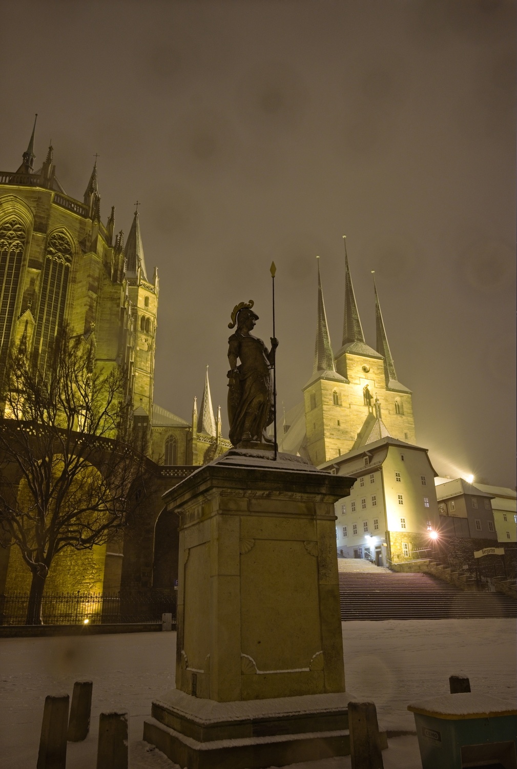Die Minervastatue mit Dom und Severikirche im Hintergrund. Der von einem direkt auf die Kamera gerichteten Leuchte entstehende Lichtstern tritt hervor, ebenso wie die Tropfen auf den Linsen.